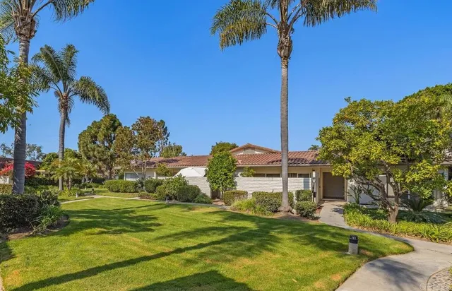 a front view of a house with a yard and palm trees