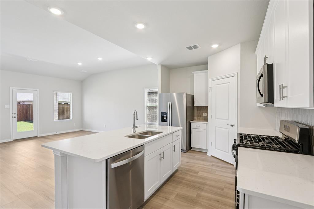 2709 Grand Cyn Street Anna, TX 75409 - Photo 11 of 40 a large white kitchen with a stove a sink a refrigerator and a cabinets