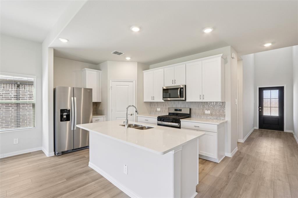 2709 Grand Cyn Street Anna, TX 75409 - Photo 12 of 40 a kitchen with stainless steel appliances a sink a stove a refrigerator cabinets and a counter top space
