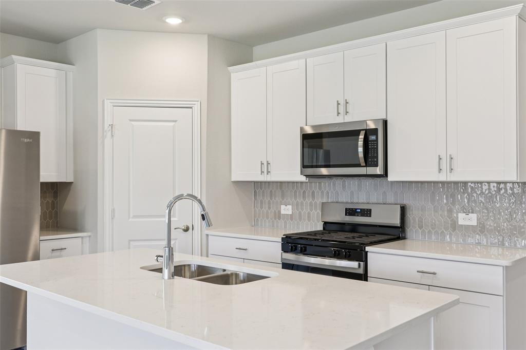 2709 Grand Cyn Street Anna, TX 75409 - Photo 13 of 40 a kitchen with granite countertop white cabinets and black appliances