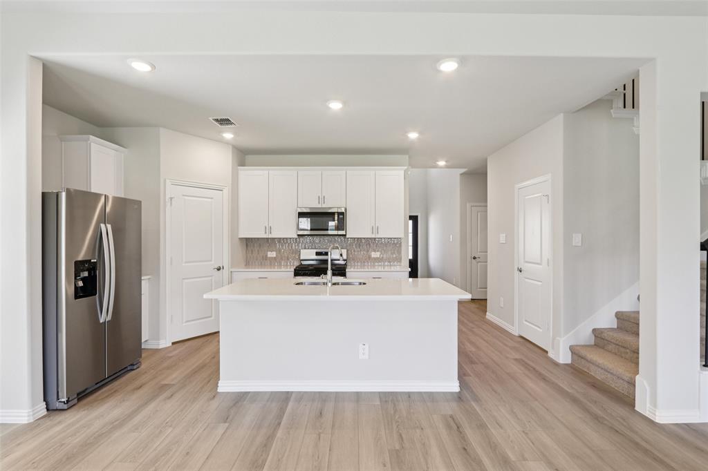 2709 Grand Cyn Street Anna, TX 75409 - Photo 15 of 40 a large white kitchen with wooden floor and stainless steel appliances