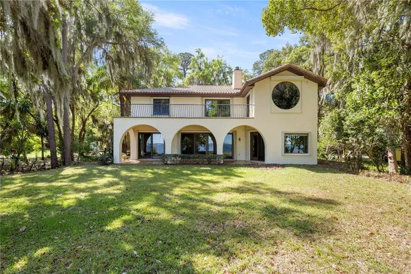 a front view of a house with garden and trees