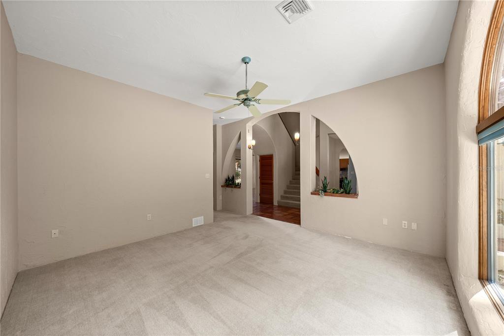 12621 Southeast Sunset Harbor Road Weirsdale, FL 32195 - Photo 20 of 54 an empty room with chandelier fan and windows