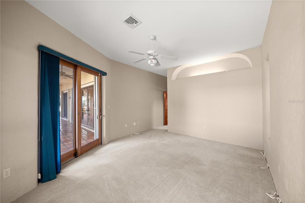 12621 Southeast Sunset Harbor Road Weirsdale, FL 32195 - Photo 23 of 54 an empty room with a chandelier fan and windows