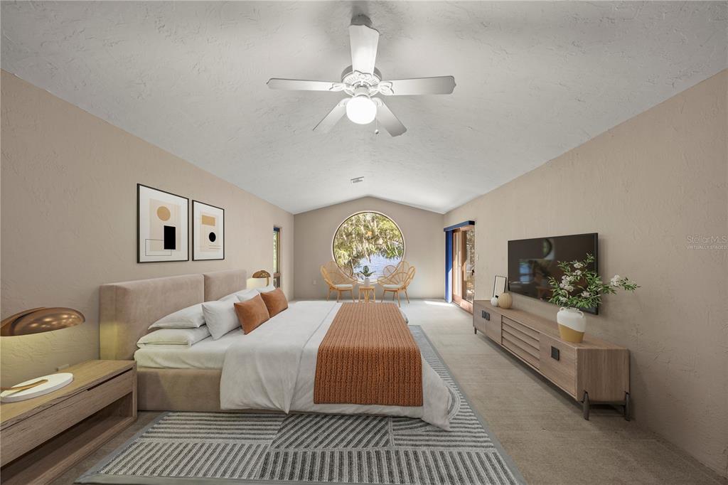 12621 Southeast Sunset Harbor Road Weirsdale, FL 32195 - Photo 28 of 54 a spacious bedroom with a bed and a flat screen tv