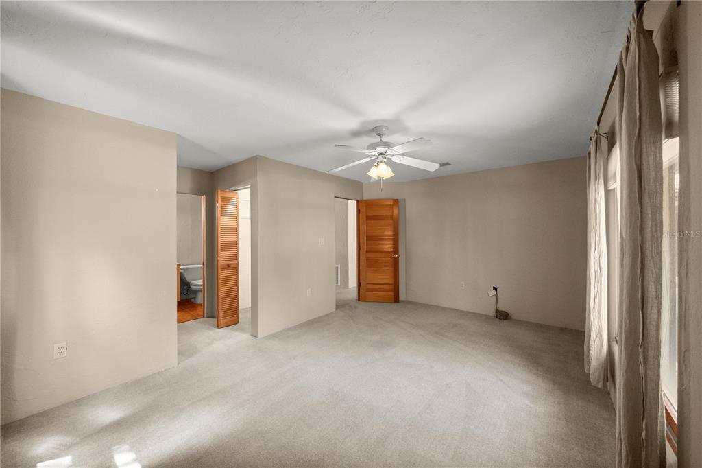 12621 Southeast Sunset Harbor Road Weirsdale, FL 32195 - Photo 33 of 54 an empty room with chandelier fan and windows