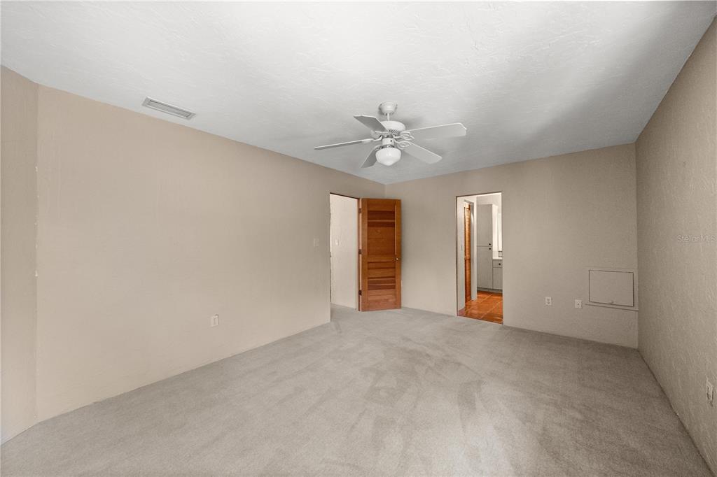 12621 Southeast Sunset Harbor Road Weirsdale, FL 32195 - Photo 35 of 54 an empty room with chandelier fan and windows