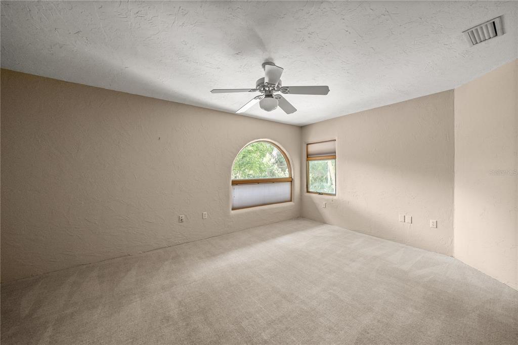 12621 Southeast Sunset Harbor Road Weirsdale, FL 32195 - Photo 36 of 54 an empty room with windows and ceiling fan