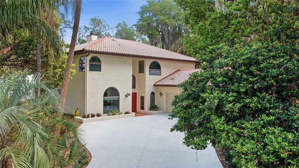 12621 Southeast Sunset Harbor Road Weirsdale, FL 32195 - Photo 4 of 54 a view of a white house with a small plants and large tree