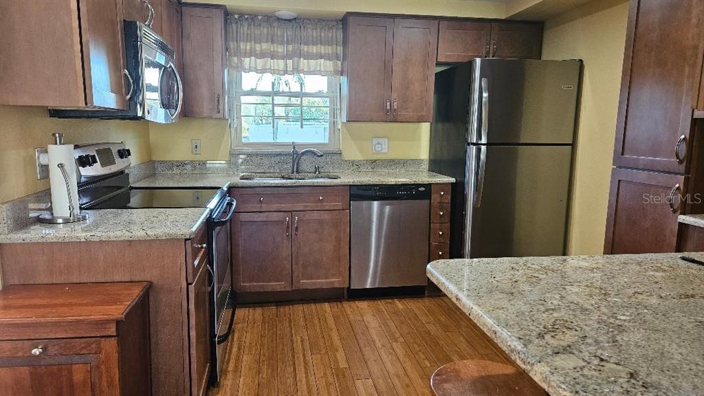4600 98th Way North, Unit 210 St. Petersburg, FL 33708 - Photo 3 of 33 a kitchen with kitchen island granite countertop a sink stove and refrigerator