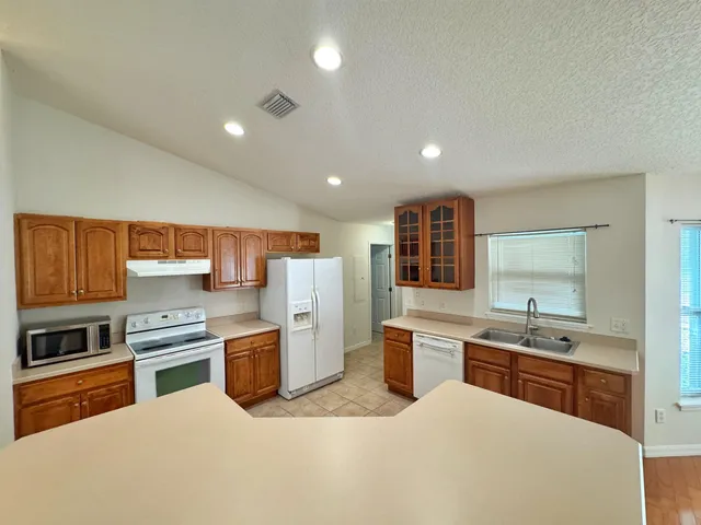 a large kitchen with stainless steel appliances granite countertop a large stove a sink dishwasher and a refrigerator with wooden floor