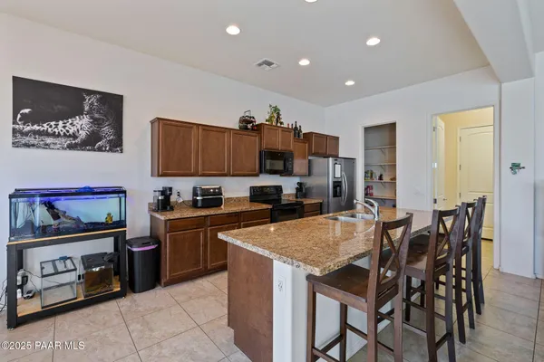 a kitchen with granite countertop a table chairs microwave and refrigerator