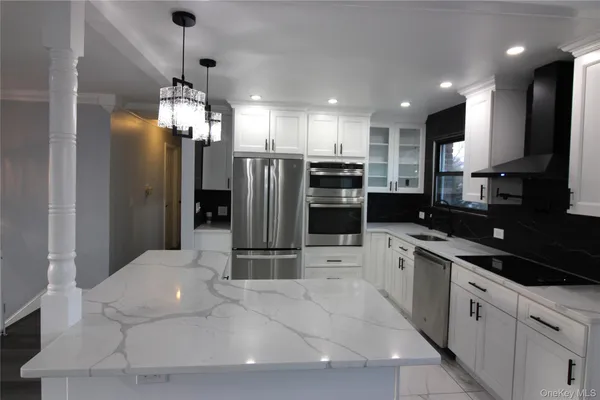 a large kitchen with stainless steel appliances kitchen island granite countertop a refrigerator and a sink