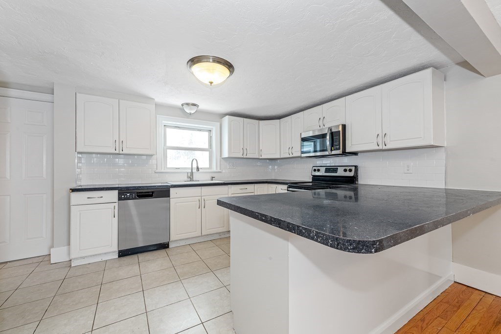 76 Rockefeller Street Randolph, MA 02368 - Photo 17 of 40 a kitchen with a sink a stove a microwave and cabinets