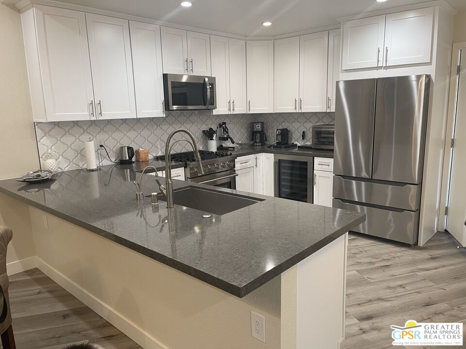 a kitchen with stainless steel appliances granite countertop a sink a refrigerator a stove a microwave and cabinets