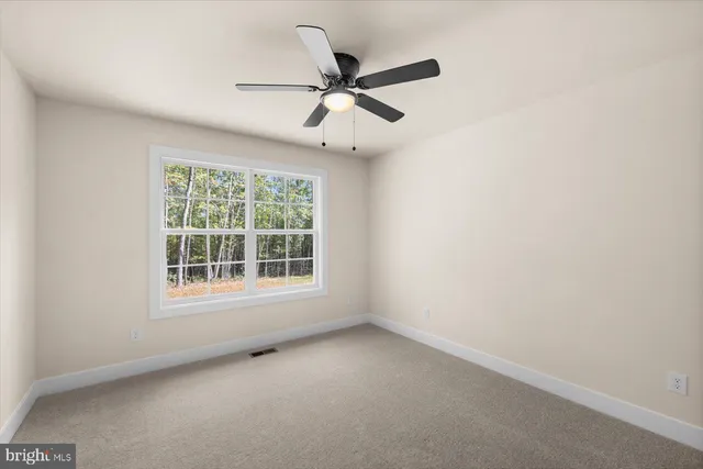 an empty room with ceiling fan and windows