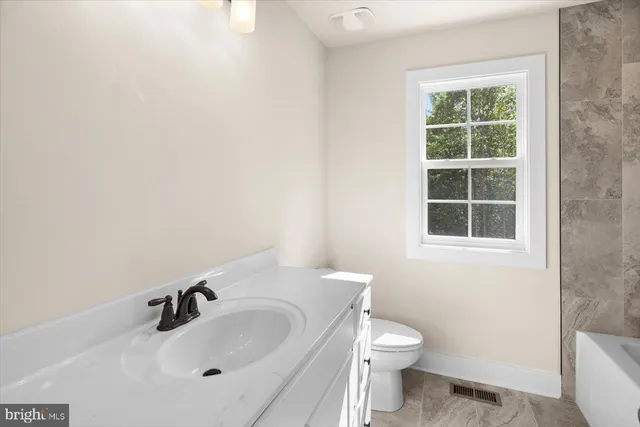 a bathroom with a sink a toilet and a window