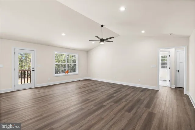an empty room with wooden floor a ceiling fan and windows