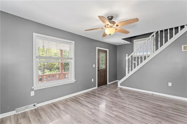 a view of an empty room with window and wooden floor