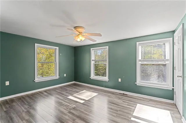 a view of an empty room with a window and wooden floor