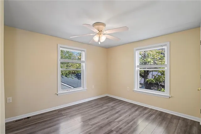 a view of a room with window a ceiling fan and wooden floor