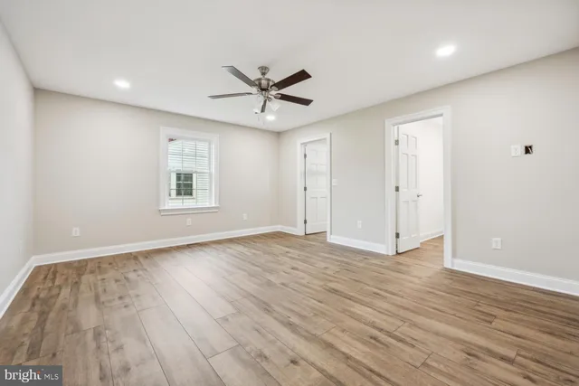 a view of empty room with wooden floor and fan