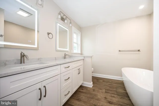 a spacious bathroom with a granite countertop sink mirror vanity and toilet