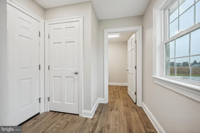 a view of a hallway with wooden floor and a bathroom