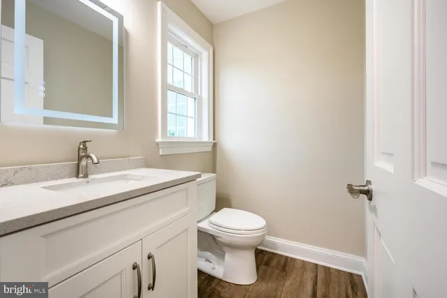 a bathroom with a granite countertop sink toilet and mirror