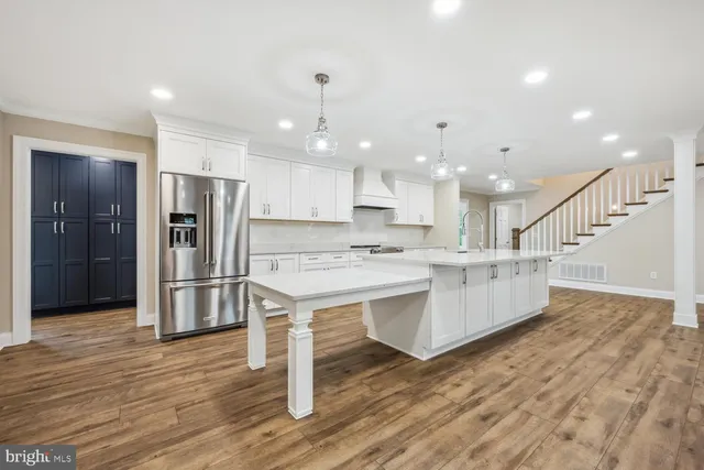 a large kitchen with a center island wooden floor stainless steel appliances and cabinets