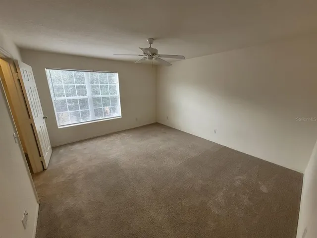 an empty room with windows and chandelier fan