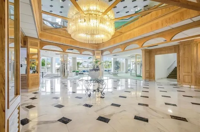 a room with lots of white furniture and chandelier