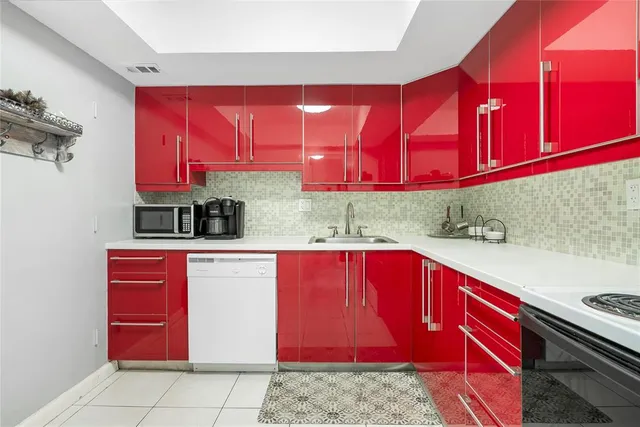 a kitchen with red cabinets and wooden floor