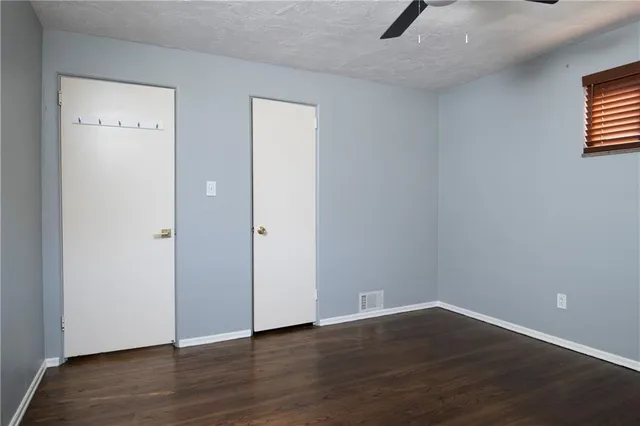 a view of an empty room with wooden floor and windows