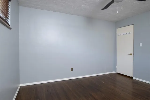 an empty room with wooden floor and fan