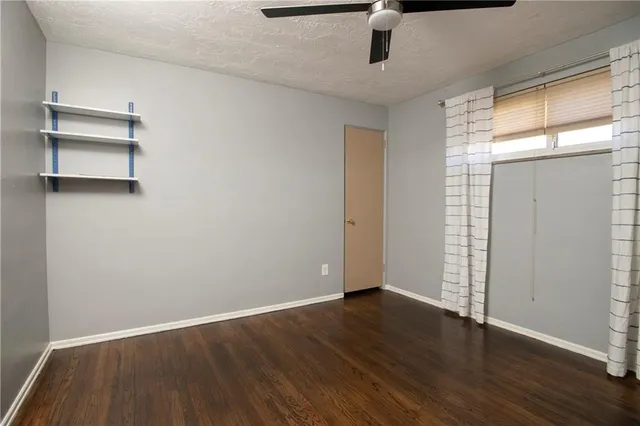 an empty room with wooden floor cabinet and windows