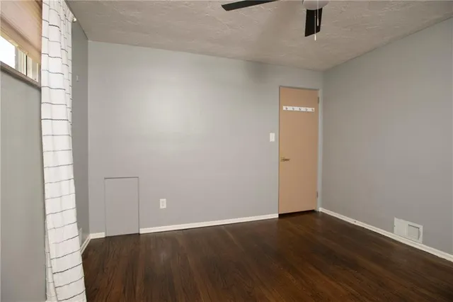 an empty room with wooden floor cabinet and windows