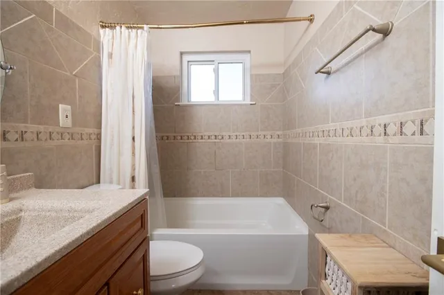 a bathroom with a granite countertop bathtub shower sink vanity and toilet