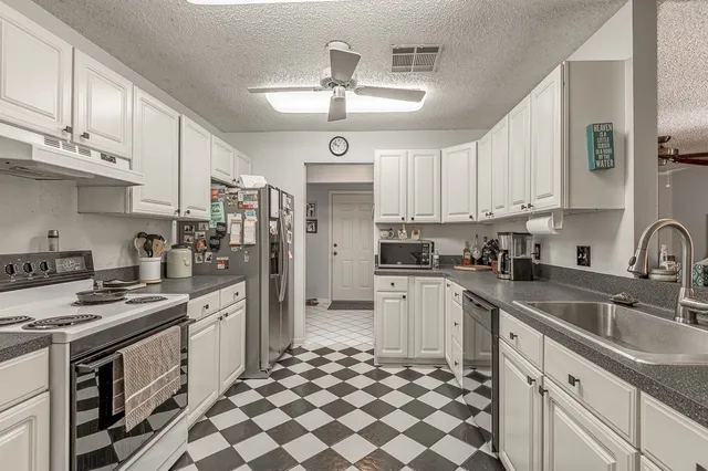 a kitchen with stainless steel appliances granite countertop a sink stove oven and white cabinets