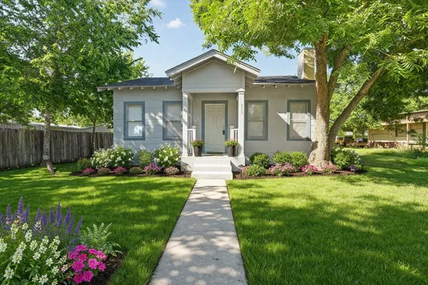 a front view of a house with a yard and potted plants