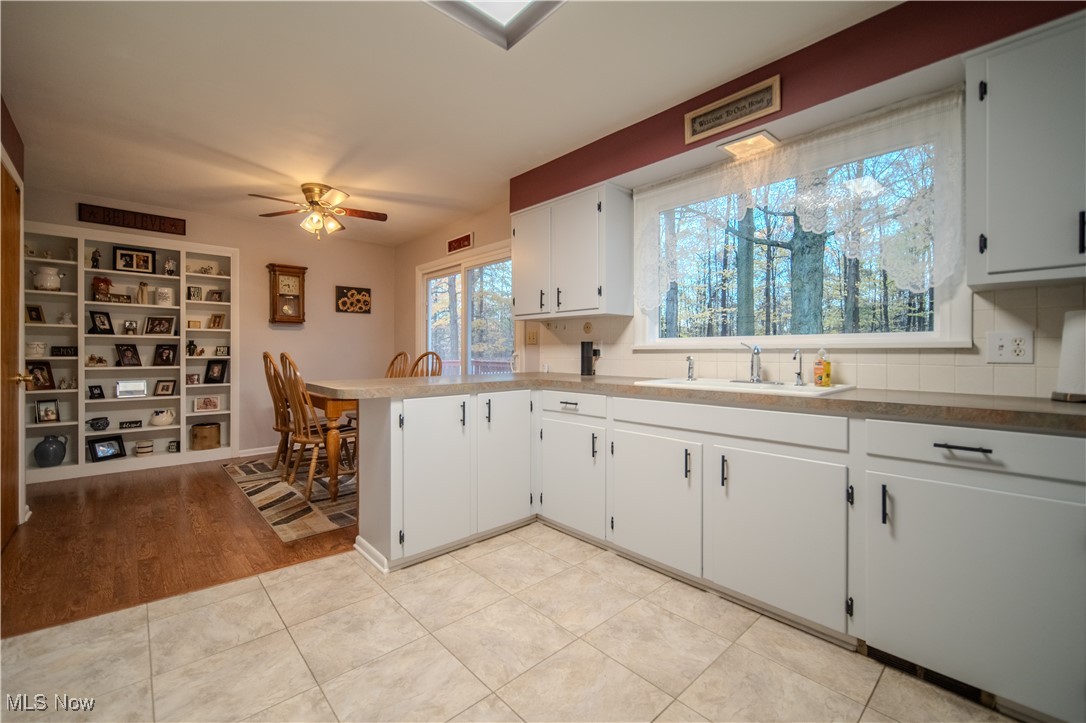 3447 Marian Road Ravenna, OH 44266 - Photo 12 of 35 Kitchen with a kitchen bar, a peninsula, light tile patterned floors, white cabinetry, and light countertops