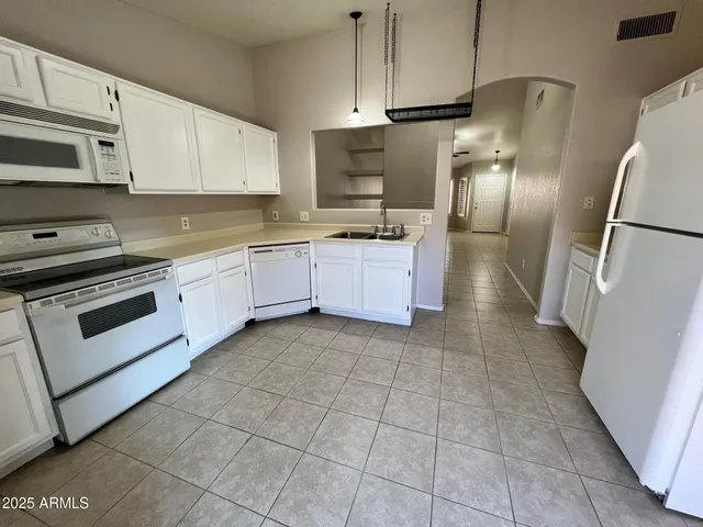 a large kitchen with cabinets a sink and stainless steel appliances