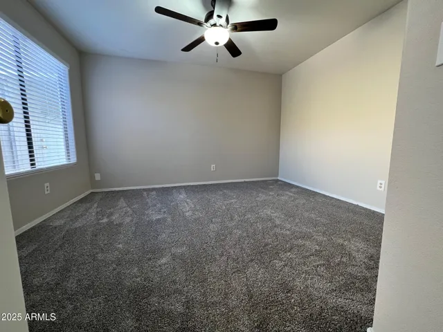 an empty room with windows and fan