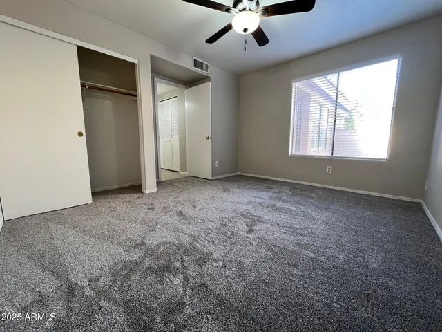 an empty room with windows and fan