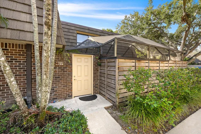 a yellow house with flower garden and wooden fence