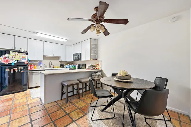 a kitchen with a dining table chairs and white appliances