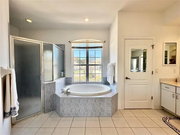 a spacious bathroom with a tub a mirror and a shower