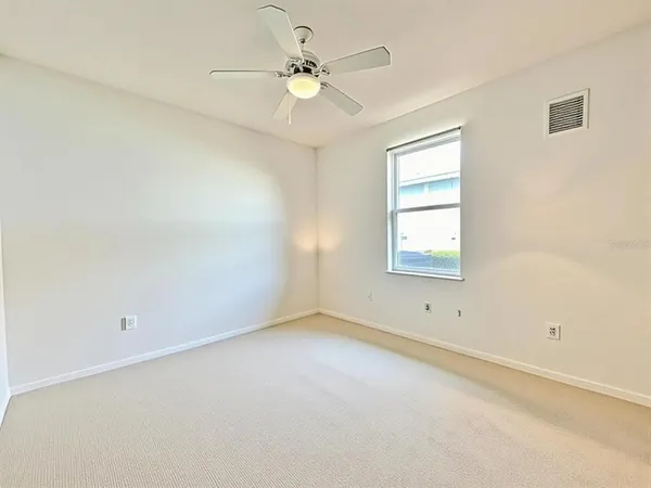 an empty room with a window and a ceiling fan