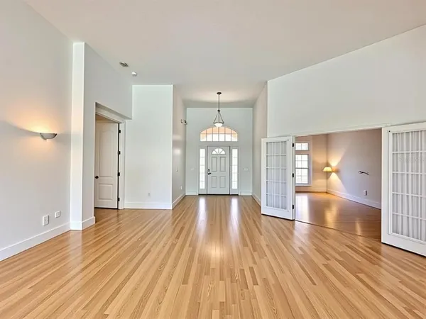 a view of an empty room with wooden floor and a window
