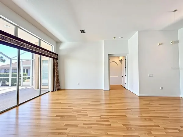 a view of an empty room with window and wooden floor